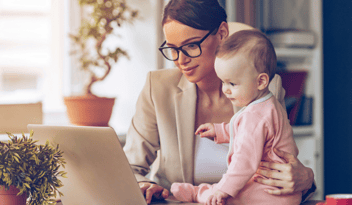 woman with glasses holding baby while looking at computer, learning about KPIs and marketing performance objectives