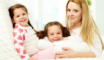 blonde mother smiling with two young brunette daughters