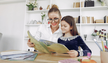 woman with glasses and hair bun reading with young girl
