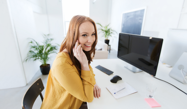 woman smiling on cell phone at desk