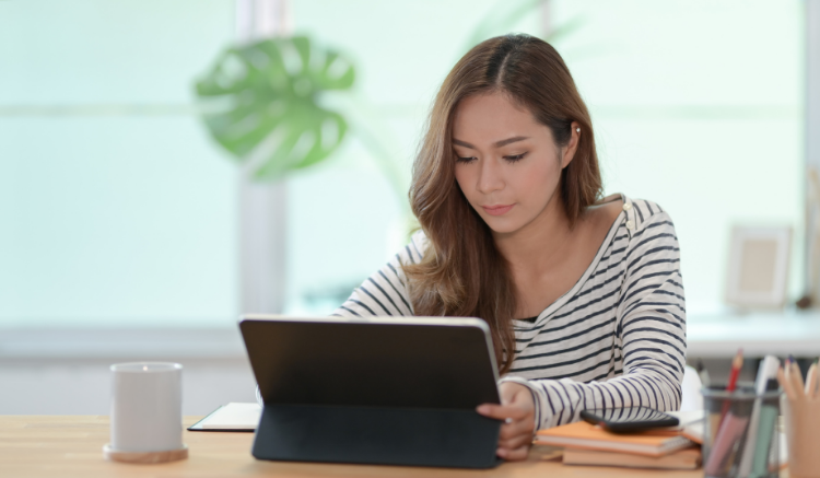 woman sitting at table, working on tablet device