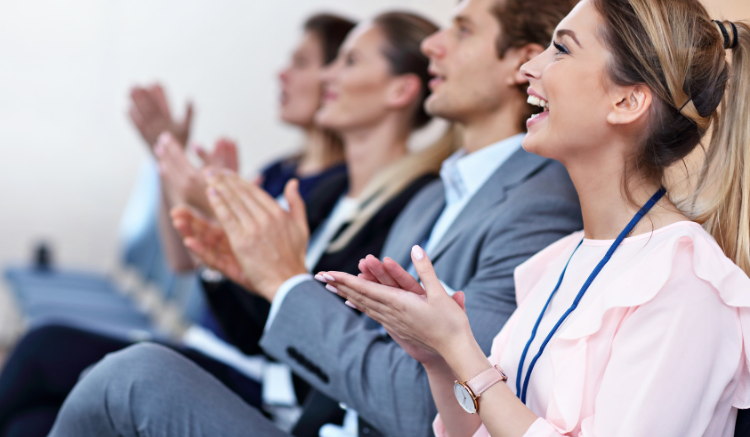 group of business people sitting in row and clapping